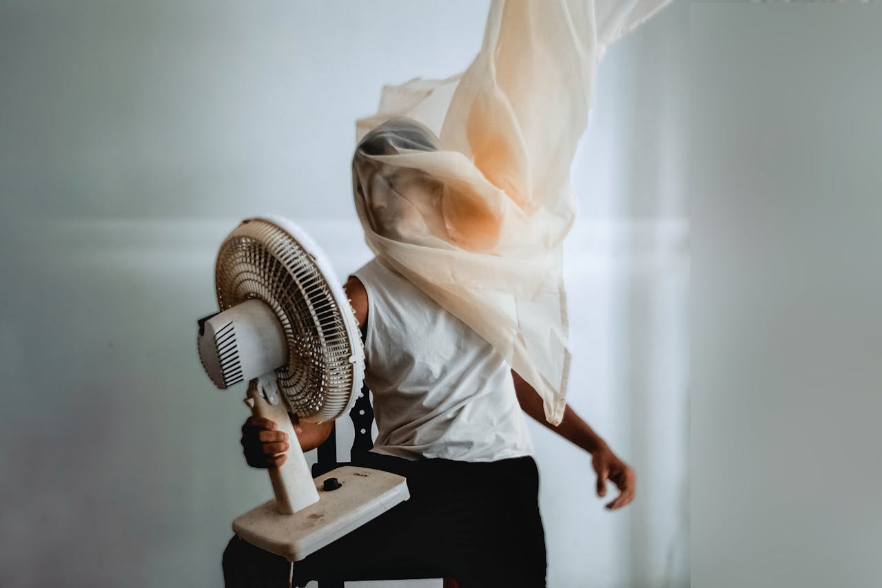 A man holding a working fan against his face